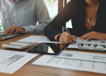 Imagem de pessoas trabalhando com vários gráficos impressos em papéis sobre a mesa