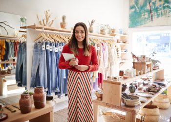 Mulher em uma loja de roupas segurando uma prancheta em suas mãos