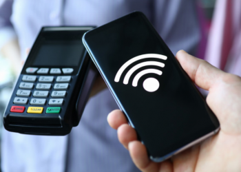 Imagem de uma mão segurando um celular e outra uma máquina de cartão