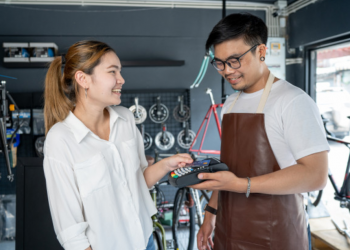 Vendedor em uma loja de bicicletas entrega máquina de cartão para cliente.