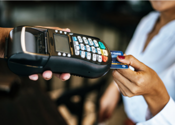 Mão feminina insere cartão em uma máquina de pagamento