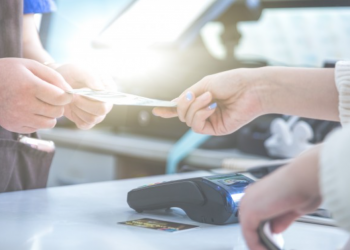 Imagem de um cliente entregando seu cartão para vendedor passar na máquina