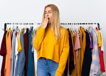 Imagem de uma vendedora em uma loja de roupas bocejando