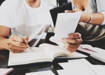 Imagem de duas pessoas olhando e fazendo anotações em um caderno